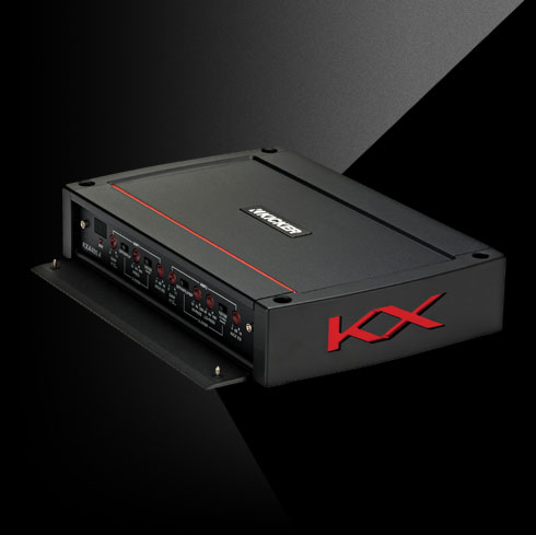 Angled view of KICKER KX amplifier with red accent lines, large side KX logo, and open control panel cover.