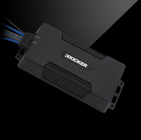 Angled view of KICKER PXA amplifier with rugged black housing and connected wiring harness.