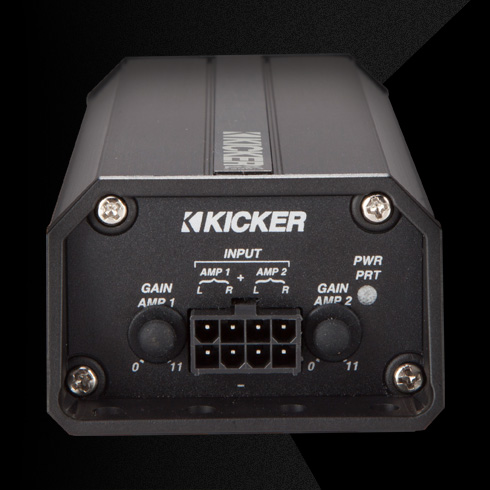 Rear view of KICKER PX amplifier showing input connector, dual gain knobs, and power indicator lights.